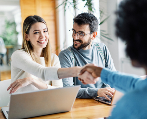 Real estate agent with couple shaking hands